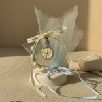 marturie religioasa cu cruce aurie pe piatra decorativa alba, margelute bleu si fundita satin