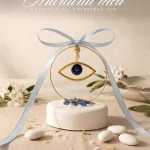 marturie simbol ochi auriu si albastru proeminent pe baza rotunda inalta alba cu pietricele decorative si fundita bleu