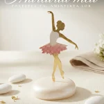 Marturie botez fetita balerina aurie cu detalii roz, așezată pe un suport perlat, decor elegant pentru masa de botez.