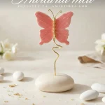 Marturie botez fetita fluture roz ceramic pe suport spiralat auriu si baza de piatra alba asezat pe masa festiva.