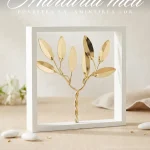 Marturii nunta maslin auriu stilizat incadrat in rama alba patrata asezat pe masa festiva.